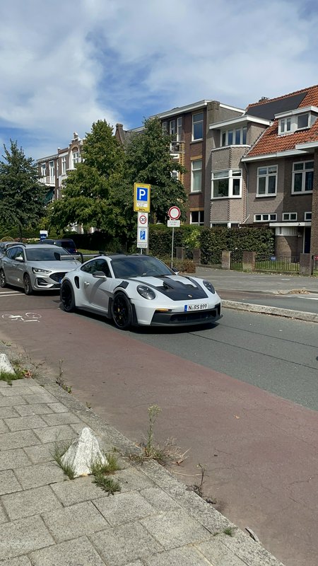 Matte silver widebody Porsche 911 GT sports car parked on a residential Dutch street on a bright sunny day
