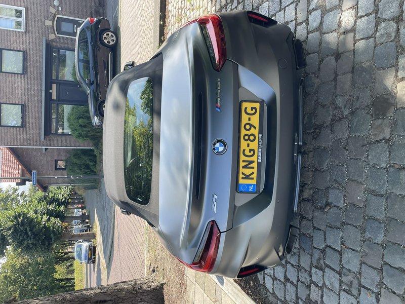Rear view of a matte satin gray BMW Z4 M40i soft-top convertible parked on a cobblestone resident...