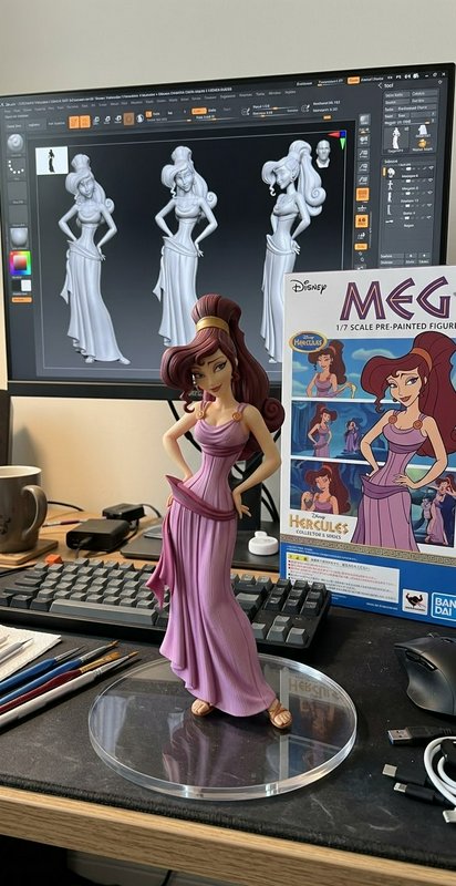 Finished painted Megara Disney Hercules figurine sits on an artist desk next to its 3D sculpt pre...