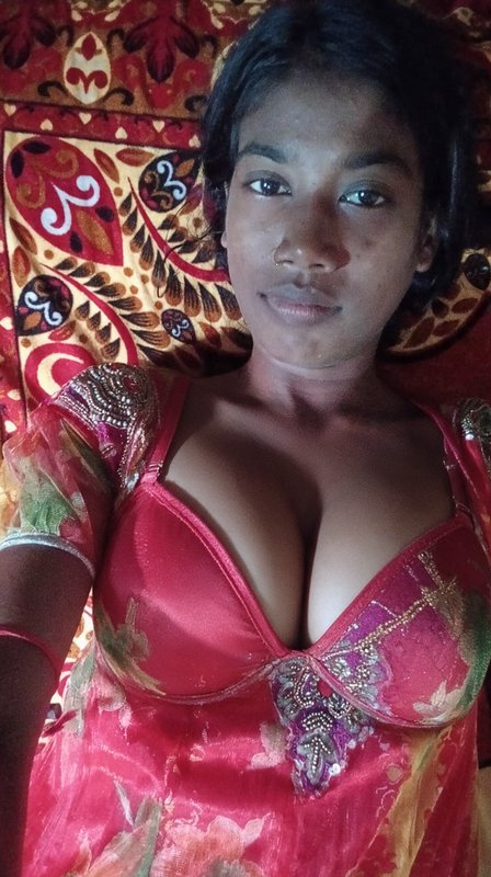 Young South Asian woman reclining against an ornate patterned bedspread taking a casual selfie