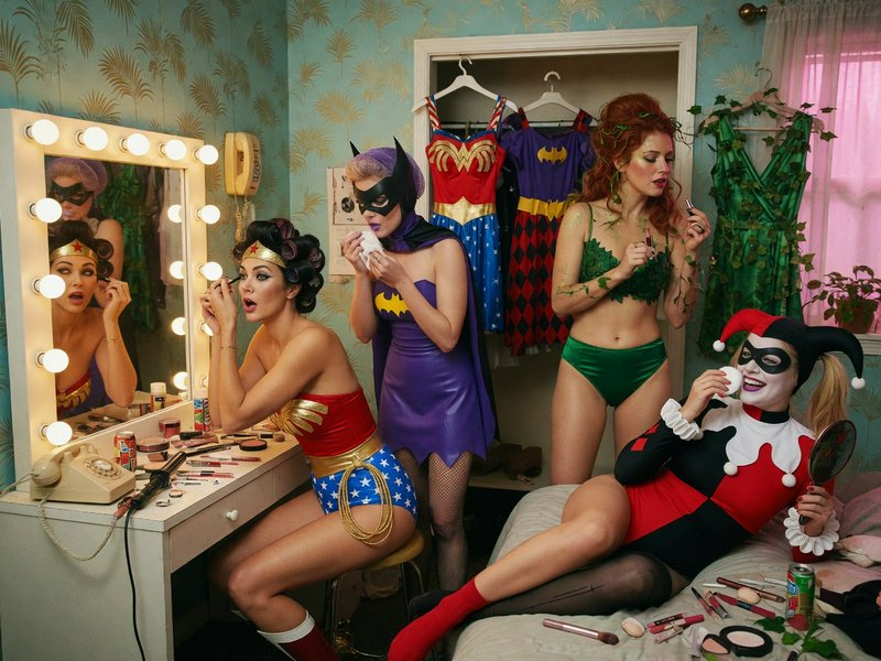 Original 1980s Wonder woman, Original 1960s Batgirl, Original 1960s Harley Quinn, Original 1960s Poison Ivy, in a hotel room, all in various states of dress,  getting ready for a night out, makeup,  vanity mirror,  dresses on hangers, subsurface scattering,  skinpores