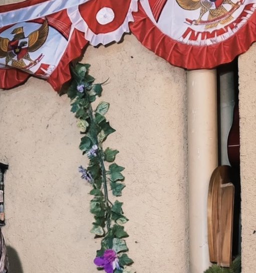 Festive red and white eagle emblem bunting hangs above an artificial floral ivy garland on a text...