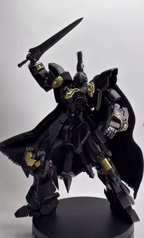 Custom black and gold knight-style Gundam mecha figure with fabric cape, holding a raised sword o...