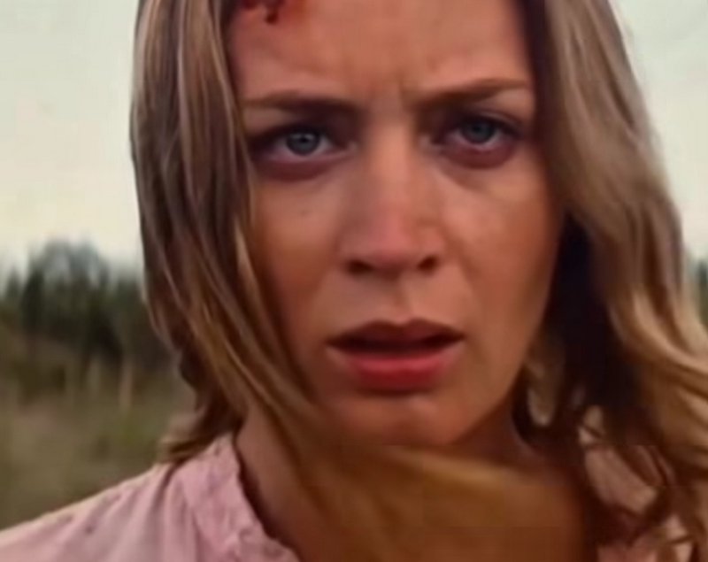 Close-up of distressed injured blonde woman with a forehead cut, standing in a hazy rural outdoor...