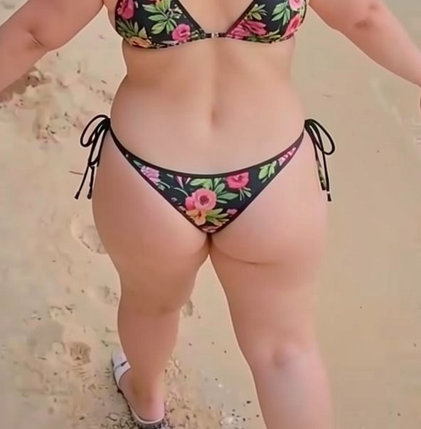 Close-up rear view of a curvy woman in a black floral print tie-side bikini standing on light tan...