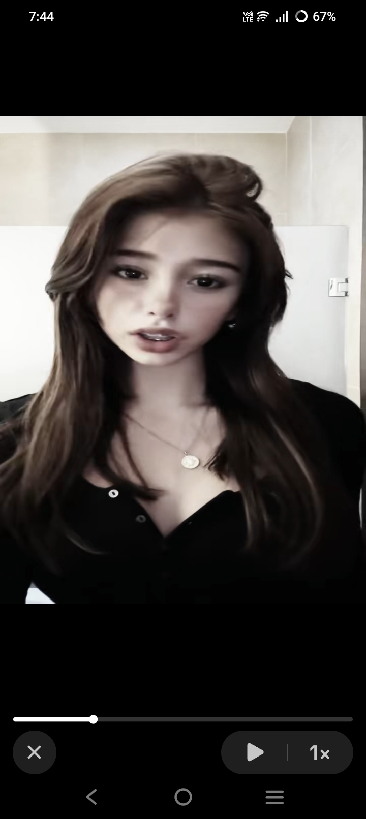Soft edited portrait of a young woman with long wavy brown hair displayed in a mobile video player