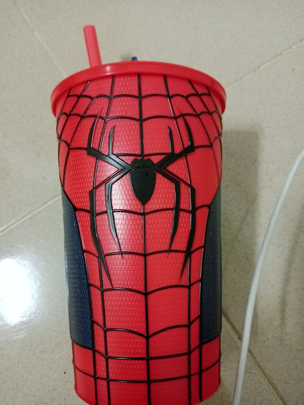 Close-up of a Spider-Man themed plastic tumbler with red lid, straw, embossed web pattern and spi...