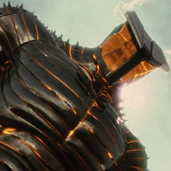 Low angle view of a giant spiked armored fire giant holding a molten hammer against a pale hazy sky