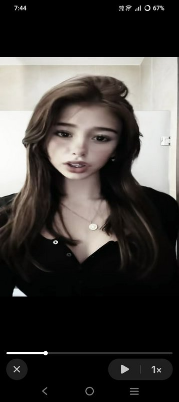 Soft edited portrait of a young woman with long wavy brown hair displayed in a mobile video player