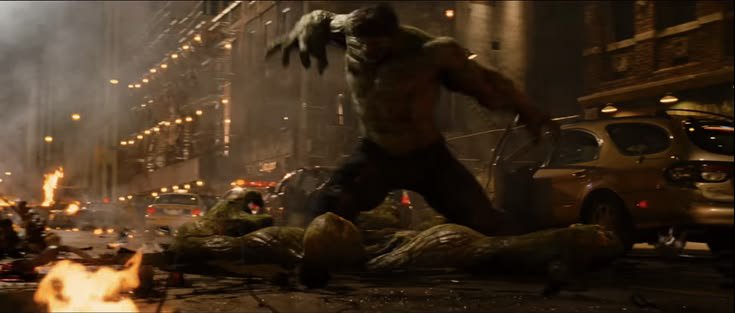 Hulk stands over a giant reptilian foe on a burning, wrecked city street at night