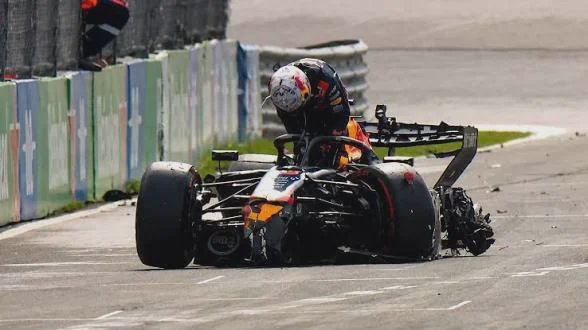 F1 driver leans out of severely damaged Red Bull race car following a crash on a paved grand prix...