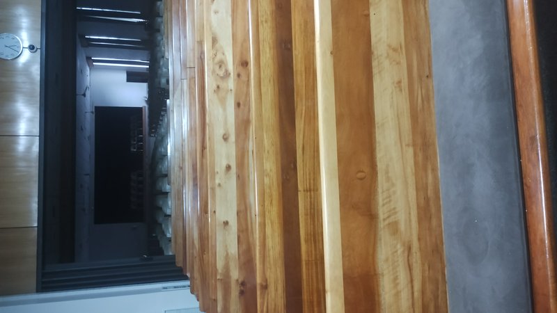 Close-up downward view of polished striped wooden stair treads with an office hallway visible in the background