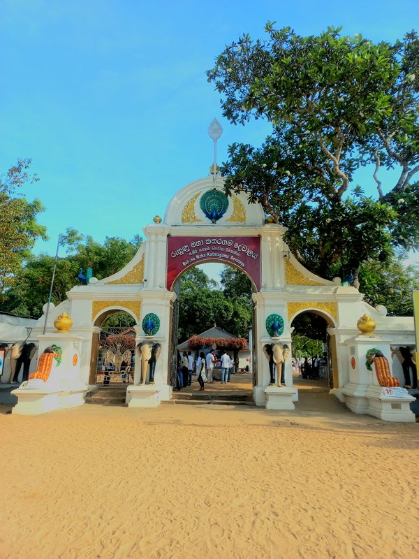 Ornate main entrance gate of Ruhunu Maha Kataragama Devalaya, Sri Lanka, under bright clear blue sky