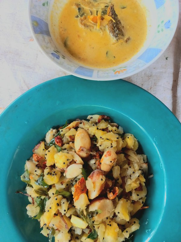 Top down view of a teal plate of spiced potato stir fry, paired with a bowl of golden creamy fish...