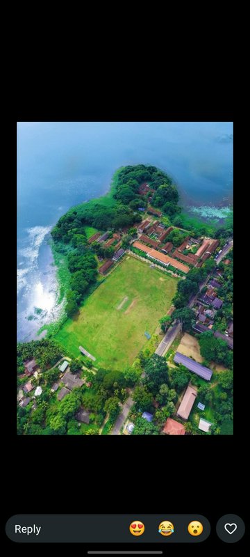 High angle aerial view of a tropical lakeside campus with a large grass sports field