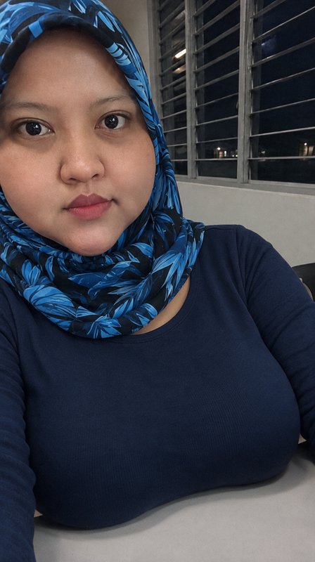 Closeup selfie of a woman wearing a blue leaf-patterned hijab indoors at night