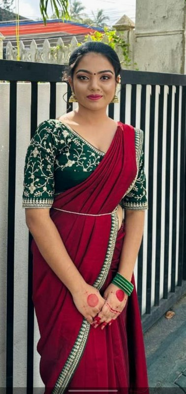 Young Indian woman in maroon saree with embroidered green blouse, posing outdoors in traditional ...