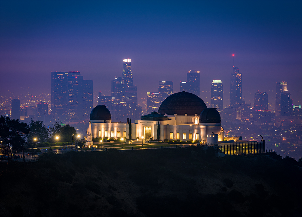 Griffith Observatory lit up at night with the Los Angeles skyline in the distance.