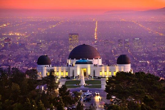Griffith Observatory with domes overlooking a glowing Los Angeles cityscape at sunset