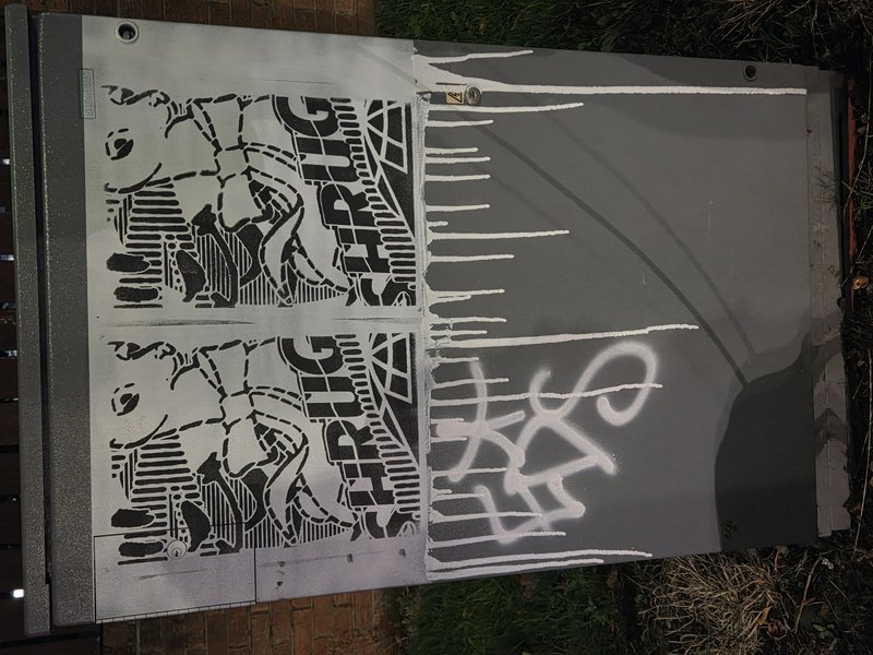 Monochrome stencil graffiti and spray paint tags on a grey outdoor metal utility box
