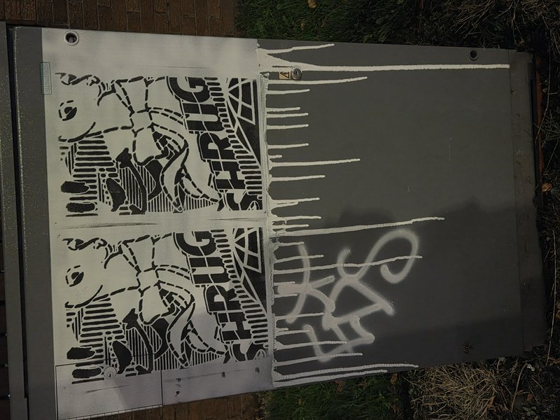 Black and white stencil graffiti painted on a grey outdoor metal utility box