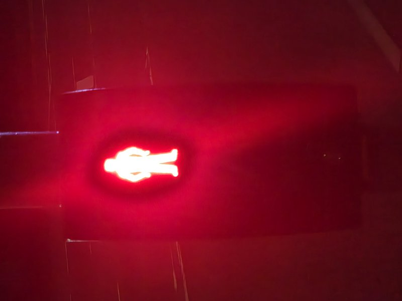 Illuminated red standing pedestrian stop traffic signal glowing against a dark nighttime background