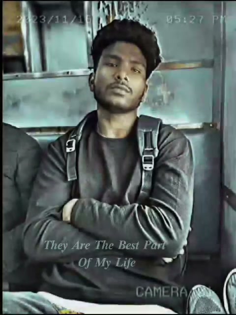 Young South Asian man seated on public transit with crossed arms, backpack, retro cam overlay and...