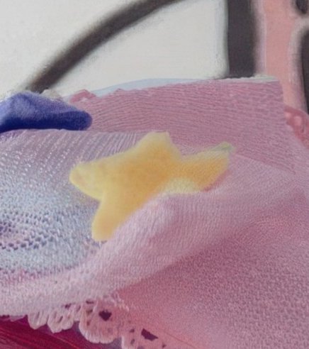 Close-up of soft pastel pink knitted baby blanket with fuzzy yellow star applique and delicate la...