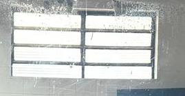 Looking through a smudged grimy grid-paned security window at bright overexposed exterior light