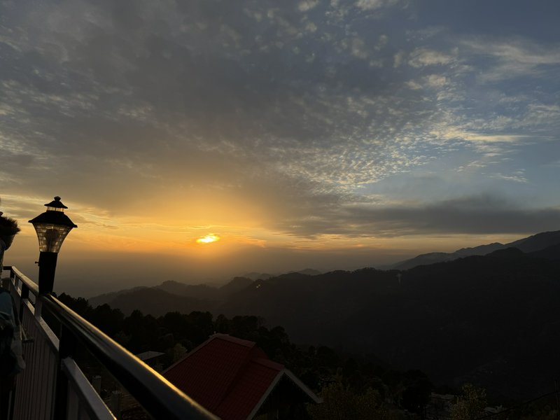 Golden sunset viewed from a hilltop balcony over misty layered mountain ranges