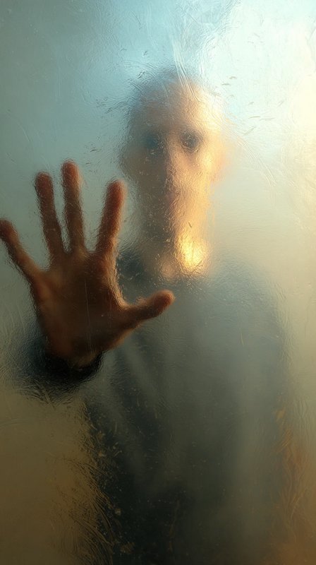 Eerie gaunt humanoid figure pressing an outstretched hand against textured fogged frosted glass