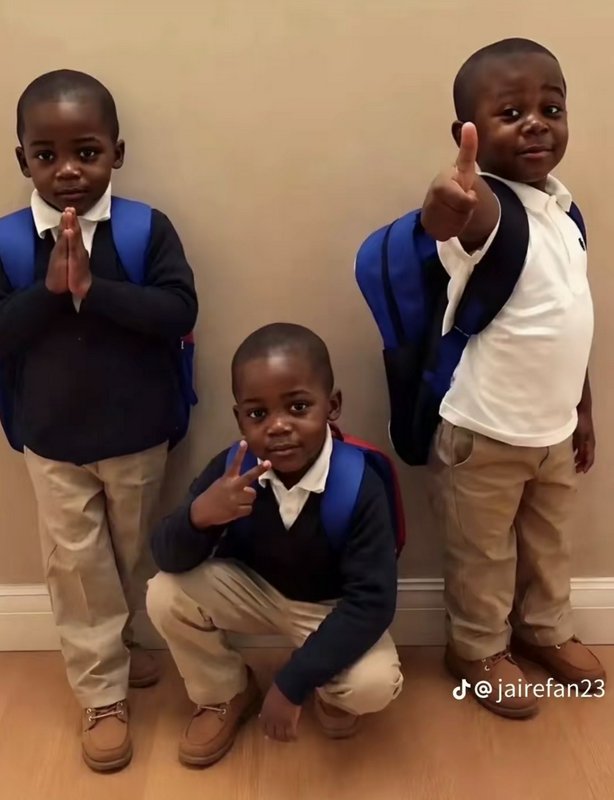 Three young Black boys in matching school uniforms and backpacks strike distinct playful poses fo...