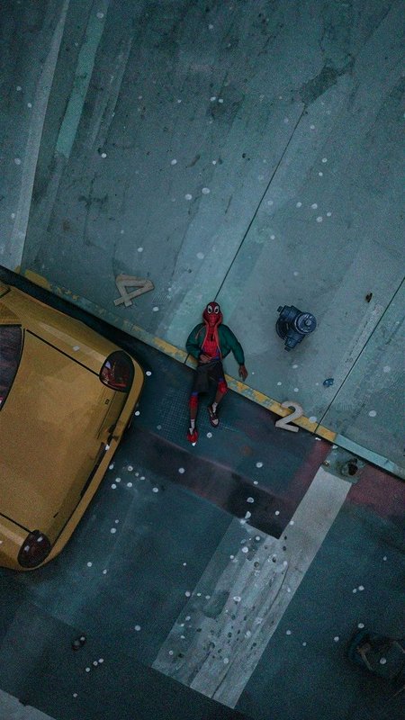 Top-down aerial view of Miles Morales as Spider-Man sitting on a snow-dusted city curb next to a ...