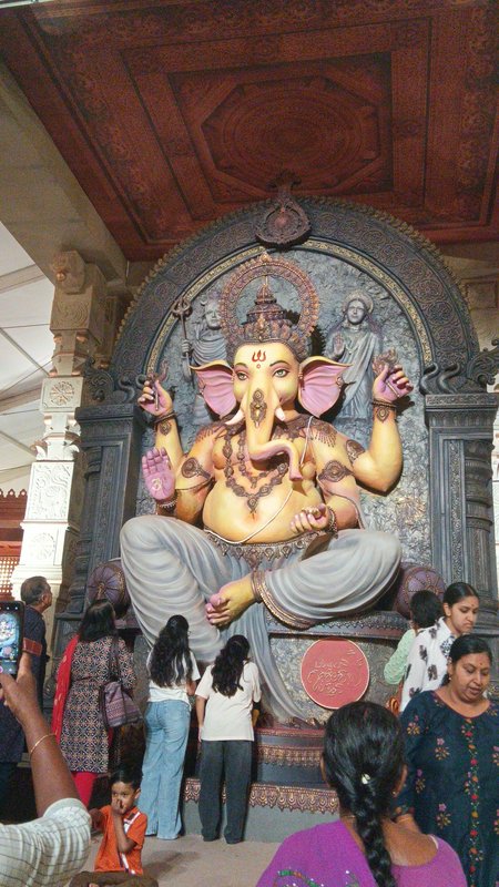 Large ornate Lord Ganesha statue surrounded by visiting devotees at a decorated Ganesh Chaturthi ...