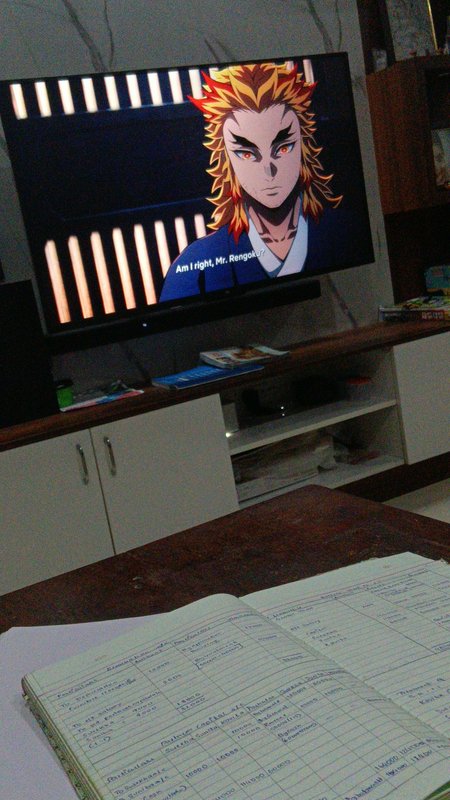 Wall mounted TV displaying Kyojuro Rengoku from Demon Slayer, with an open study notebook on a fo...