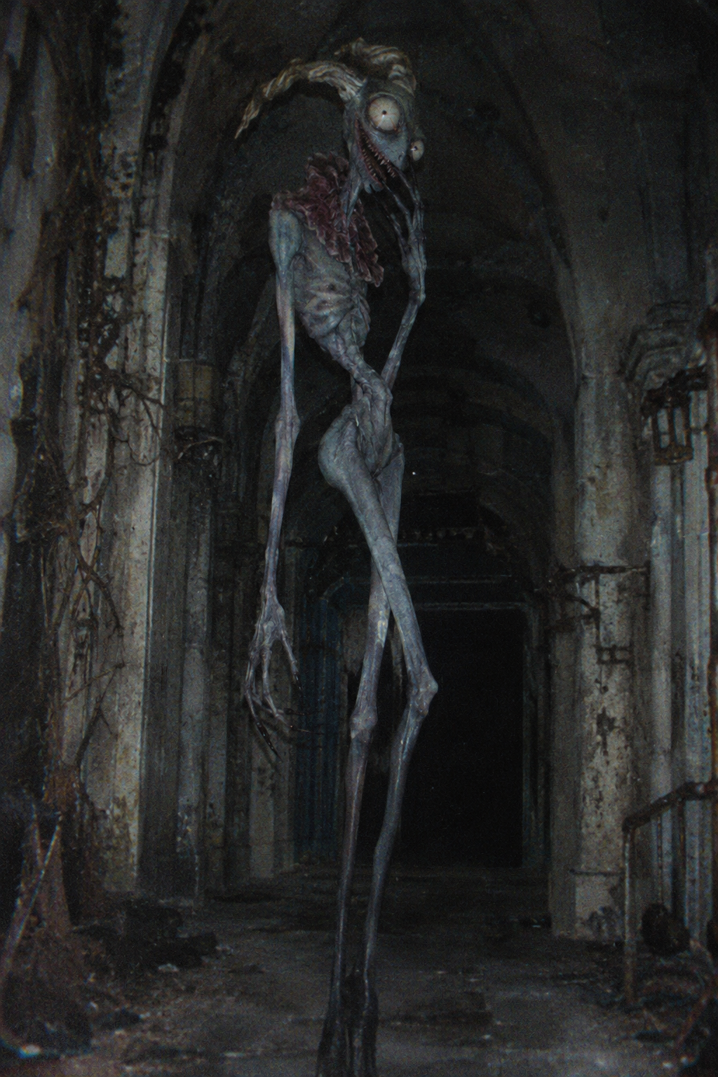Tall gaunt horned skeletal monster stands in a decaying dark arched stone corridor