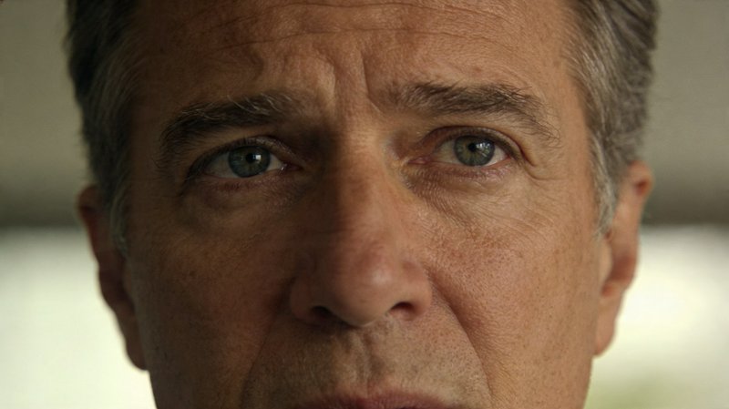 Close-up portrait of a middle-aged man with blue-green eyes and weathered skin.