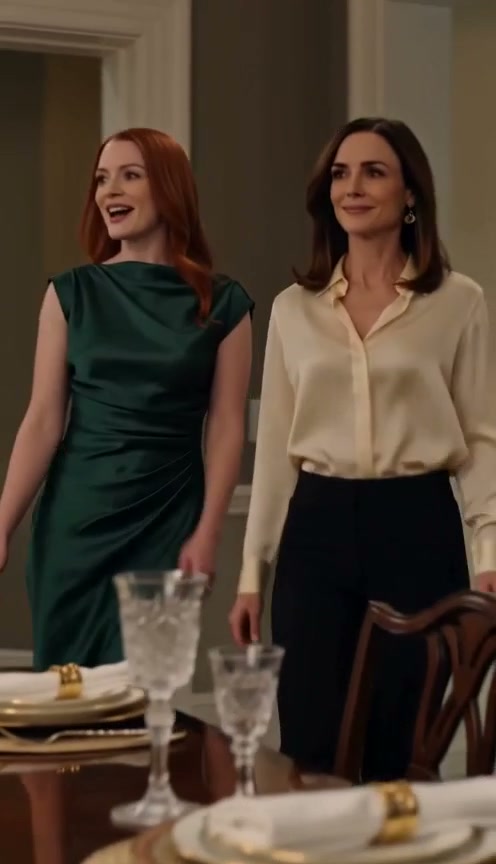 Two stylish women stand beside an elegantly set formal dining table in a classic home dining room.