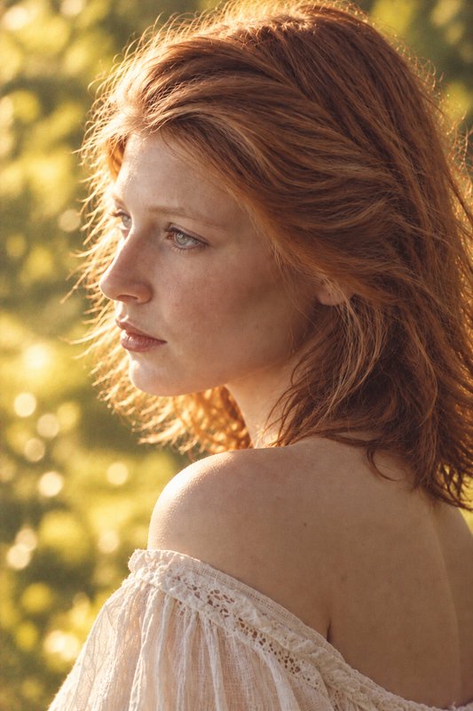 Profile portrait of a red haired woman bathed in warm golden hour outdoor sunlight