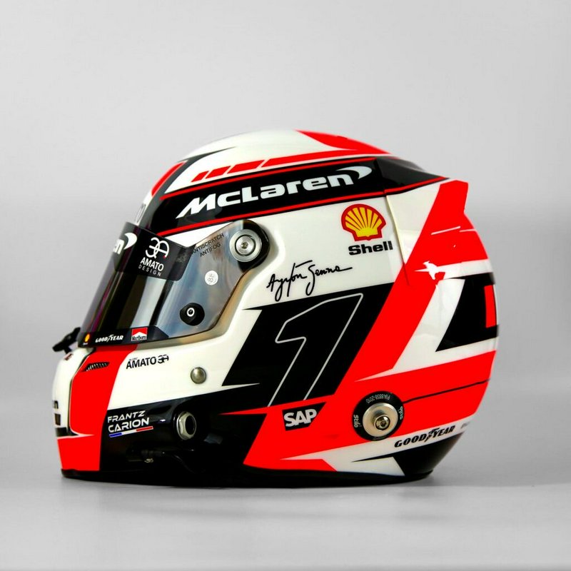 Custom McLaren F1 racing helmet with Ayrton Senna signature and sponsor decals on a plain grey ba...