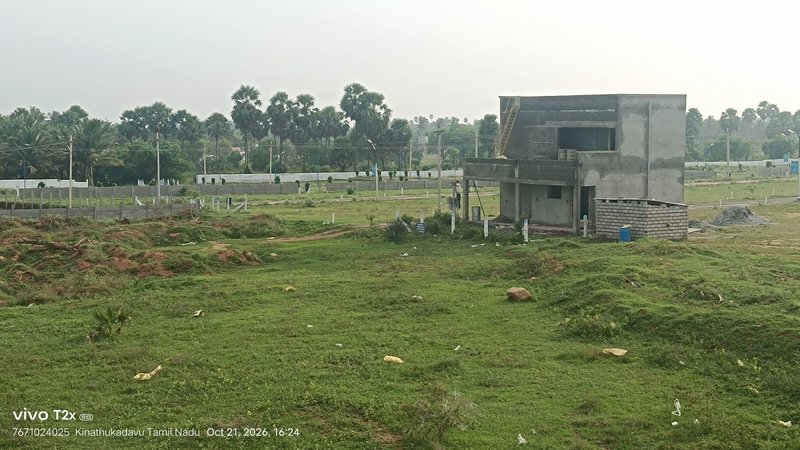 Unfinished two-story concrete house on a grassy residential development plot in rural Tamil Nadu