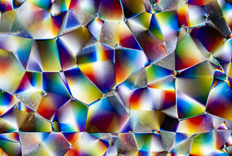 Close-up of iridescent, multi-colored polygonal pattern with shimmering edges.