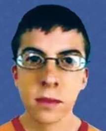 Front facing ID headshot of a young man with wire-rimmed glasses and short dark hair against a so...