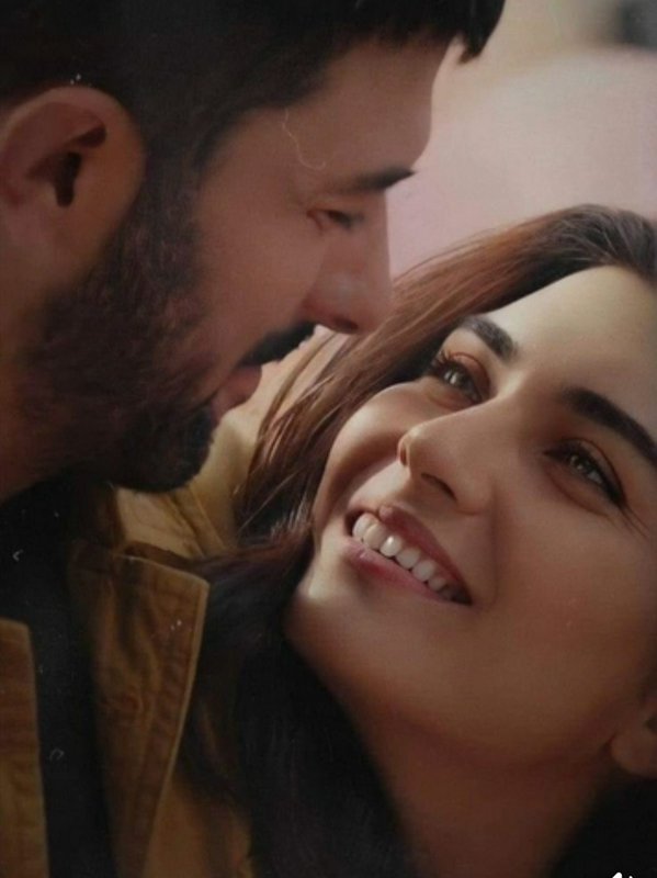 Bearded man leans close to a smiling woman sharing a tender, intimate romantic moment