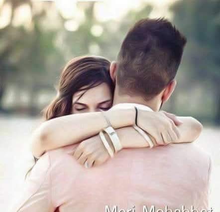 Young couple sharing a tender hug outdoors, woman resting her closed eyes against her partner's s...