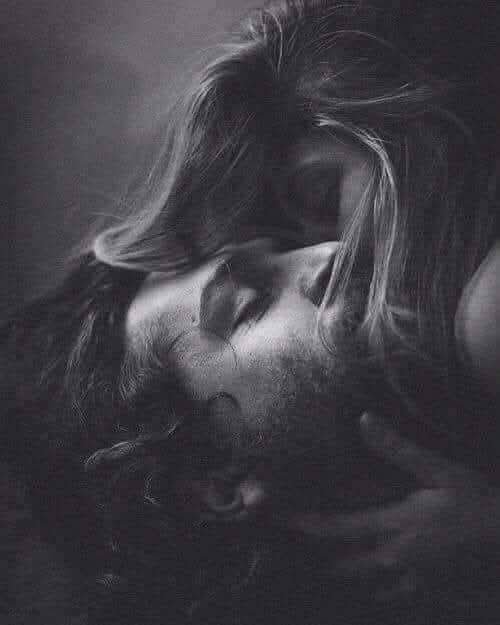 Dramatic low-key black and white portrait of a bearded long-haired man resting with his eyes closed