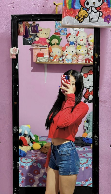Young woman in a red crop top takes a mirror selfie in a kawaii Hello Kitty themed bedroom