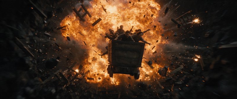 Group of people in a flying wooden cart escape a massive fiery explosion with flying debris scatt...