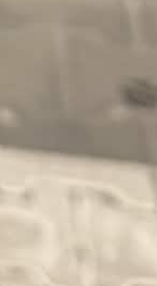Blurry close-up of a light gray surface with faint white patterns.