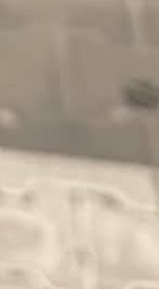 Blurry close-up of a light gray surface with faint white patterns.